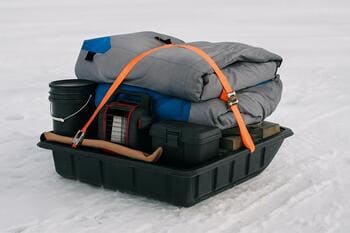 Loaded sled on the ice with a pack checklist card tucked under the rope